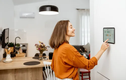 Woman controlling her home smart meter from a screen in a kitchen