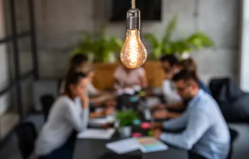 team sat around conference table with lightbulb overhead