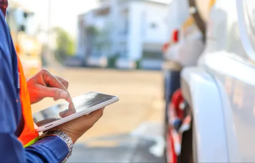 Person looking at tablet next to vehicle