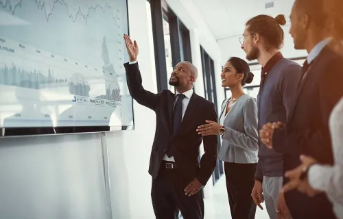 A group of professionals analyzing data on a large screen in an office setting