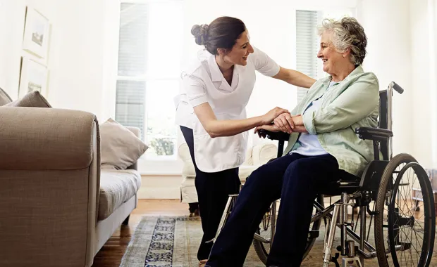 Healthcare worker comforting elderly patient in wheelchair