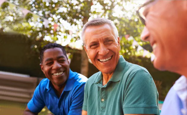 Three men sat smiling and looking content in an outdoor setting