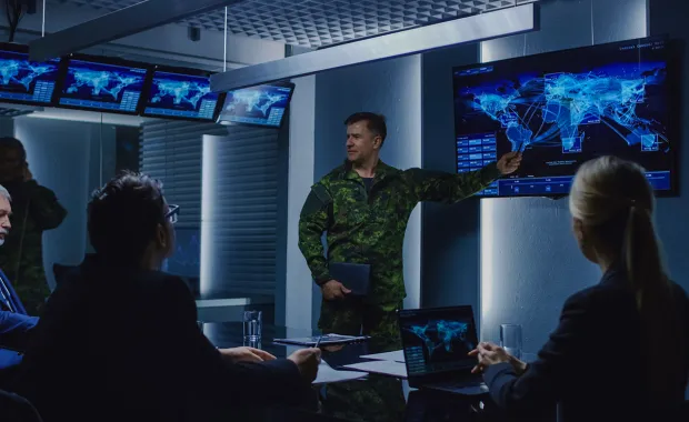 defence professionals discuss a map on a display screen