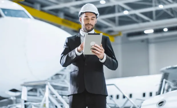 Person using tablet device stands in front of aircraft